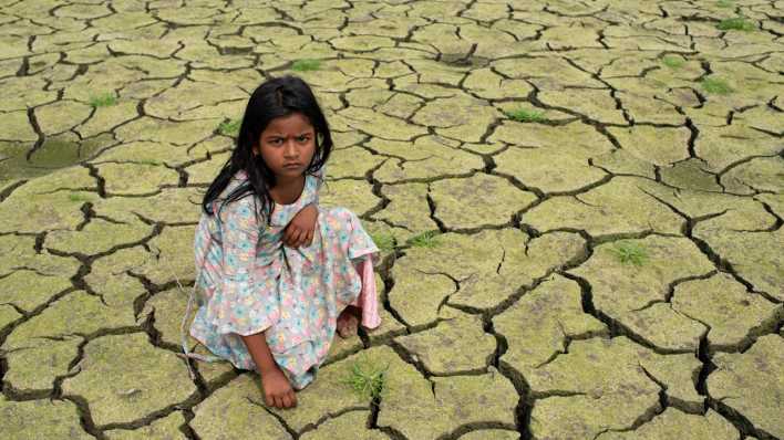 Ein Kind sitzt auf einem ausgedürrten Feld. (Bild: picture alliance / ZUMAPRESS.com | Fatima-Tuj Johora)