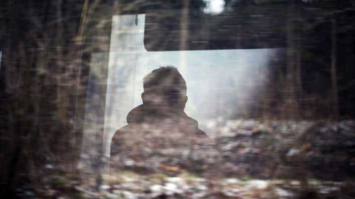 Symbolbild: Dunkle Silhouette eines Mannes und Wald spiegeln sich in einer Fensterscheibe (Bild: dpa / Karl-Josef Hildenbrand)