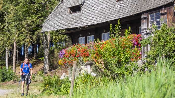 Ein Wanderer passiert ein Haus im Schwarzwald (Foto: imago images / Cavan Images)