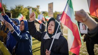 Teilnehmer demonstrieren mit Fahnen und Plakaten für Freiheit und Demokratie im Iran vor dem Reichstagsgebäude.