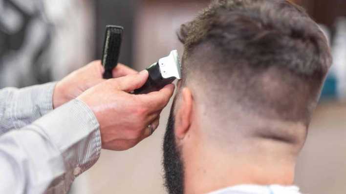 Mann bekommt in einem Friseursalon den Bart gestutzt