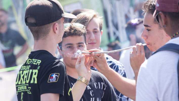 Bei einer Demonstration zünden sich junge Männer einen langen Joint an (Bild: picture alliance /Pacific Press)
