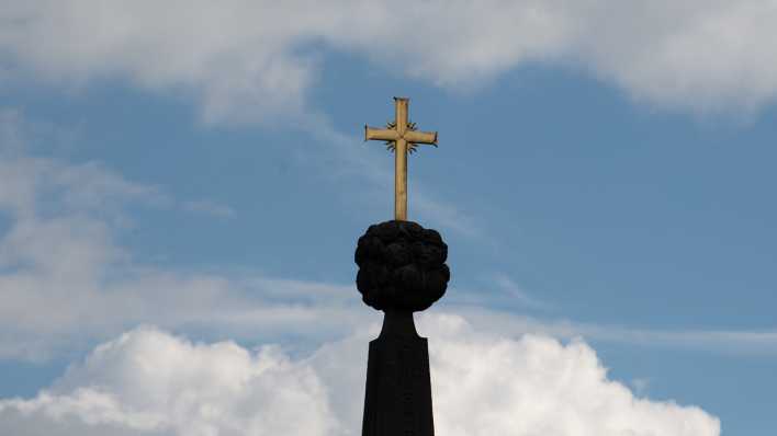 Wolken ziehen hinter einem Kreuz am Dom St. Salvator zu Fulda vorbei