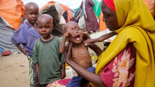 Ein geflüchtete Frau hält ihr hungerndes und schreiendes Kind in den Armen (Bild: picture alliance/dpa/AP)