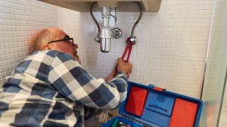 Ein läterer Heimwerker bei der Montage von neuem Waschbecken im Badezimmer (Bi9ld: picture alliance / Zoonar)