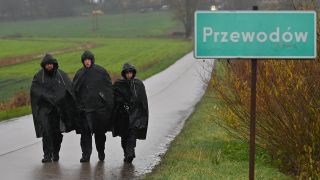 Polizisten am Orsteingangsschild des polnischen Dorfes Przewodow