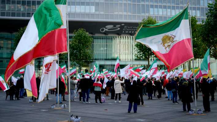 Demonstranten schwenken Fahnen, während sie an einer Solidaritätskundgebung für iranische Frauen vor einem Treffen der EU-Außenminister im EU-Ratsgebäude teilnehmen.