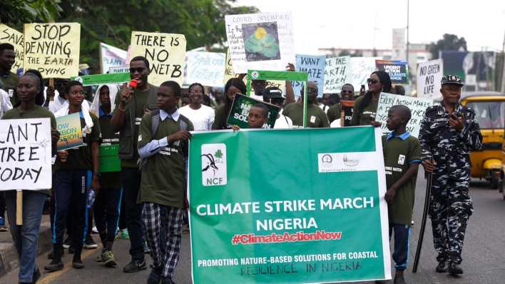 Demonstranten gehen bei einem Klimastreik mit Transparenten durch eine Straße in Nigeria.