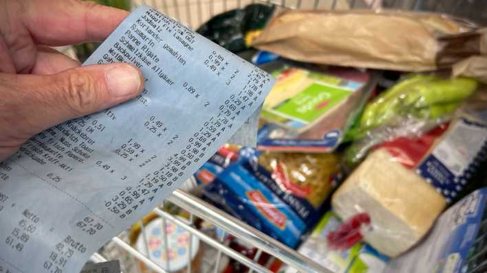 Kassenzettel neben einem Einkaufswagen mit Lebensmitteln