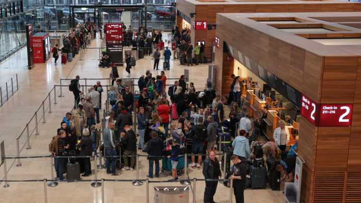 Reisende stehen an Check-In-Schaltern im Terminal 1 des Flughafens BER