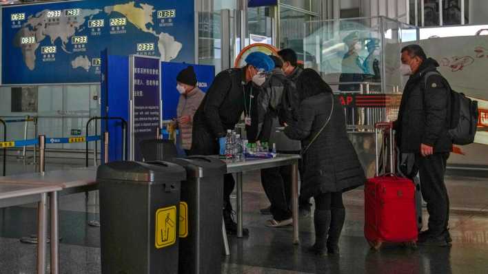 Peking: Passagiere mit Mund-Nasen-Schutz stellen sich an der Sicherheitskontrolle an