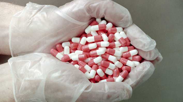 Eine Mitarbeiterin einer Arzneimittelproduktion in Lettland zeigt eine Handvoll Tabletten.