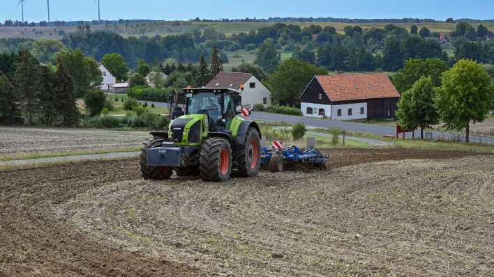 Ein Landwirt bearbeitet den Ackerboden auf einem Hügel im Landkreis Uckermark.