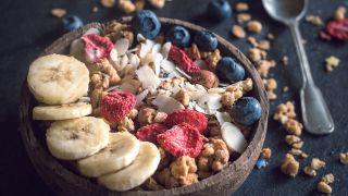 Eine Schüssel mit Müsli, Beeren, Bananenscheiben und Nüssen.