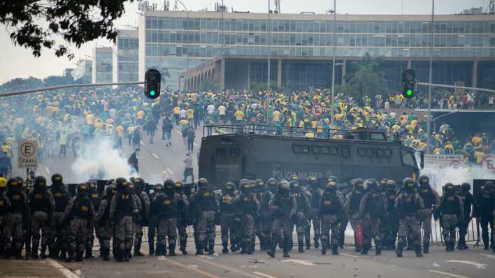 Brasilia: Anhänger des ehemaligen brasilianischen Präsidenten Bolsonaro (hinten) geraten in der Hauptstadt mit Ordnungskräften aneinander