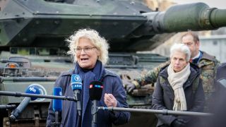 Christine Lambrecht gibt Interviews vor einem Bundeswehr-Panzer, im Hintergrund steht Marie-Agnes Strack-Zimmermann.
