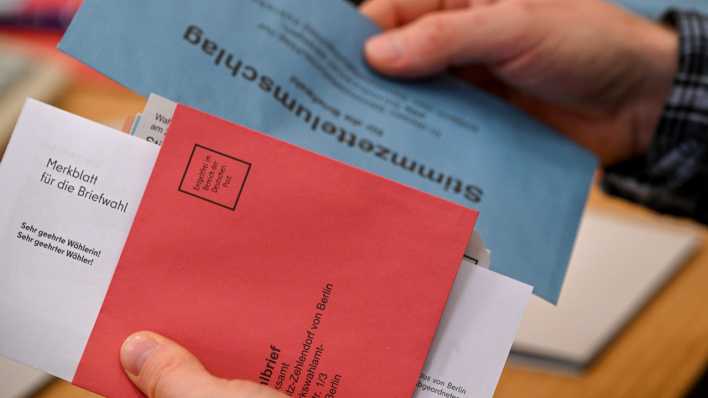 Eine Person hält Wahlunterlagen zur Briefwahl für die Wiederholungswahlen in Berlin in der Hand (Bild: dpa)