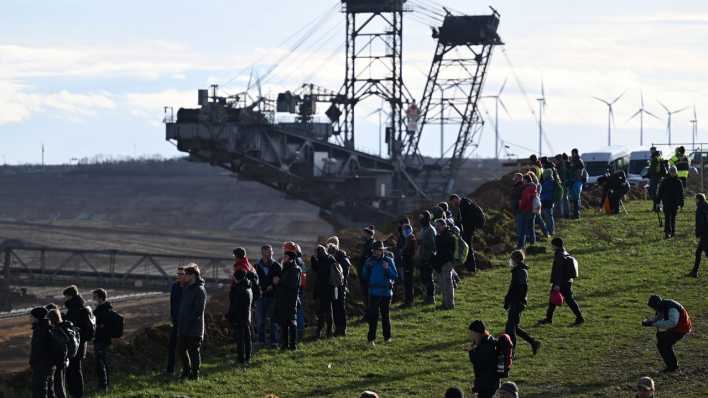 Klimaschutzaktivisten stehen vor einem Schaufelradbagger am Rand des Tagebaus in Lützerath