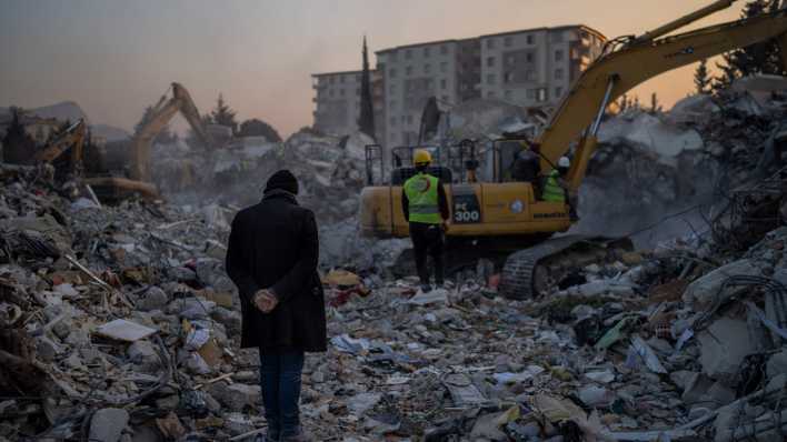 Ein Mann steht inmitten von vom Erdbeben zerstörten Häusern in der türkischen Stadt Antakya. (Quelle: Picture Alliance)