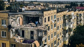 Luftaufnahme: Ein Mann räumt im ukrainischen Nikopol eine völlig zerstörte Wohnung auf.