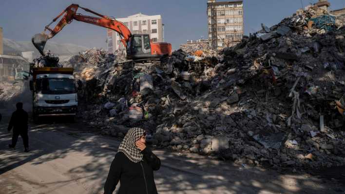 Eine Frau geht an den Trümmern von Gebäuden vorbei, die während des Erdbebens in der Türkei zusammengebrochen sind. (Bild: dpa)