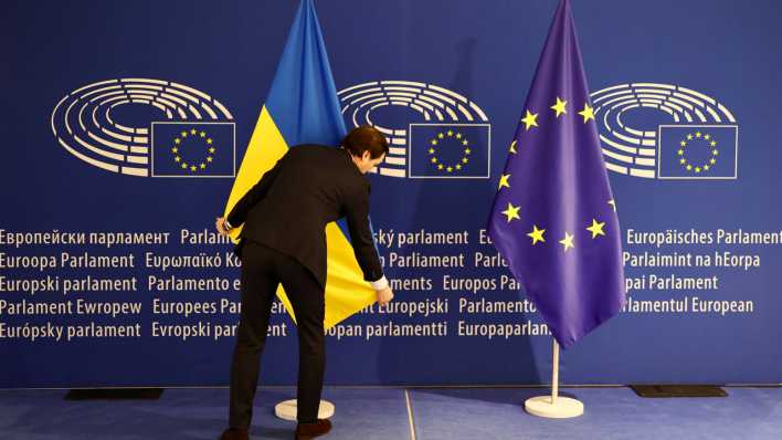 Ein Arbeiter stellt eine ukrainische Fahne vor der Ankunft des ukrainischen Präsidenten Selenskyj auf.