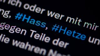 Auf dem Bildschirm eines Smartphones sieht man die Hashtags Hass und Hetze in einem Post. (Bild: picture alliance/ dpa)