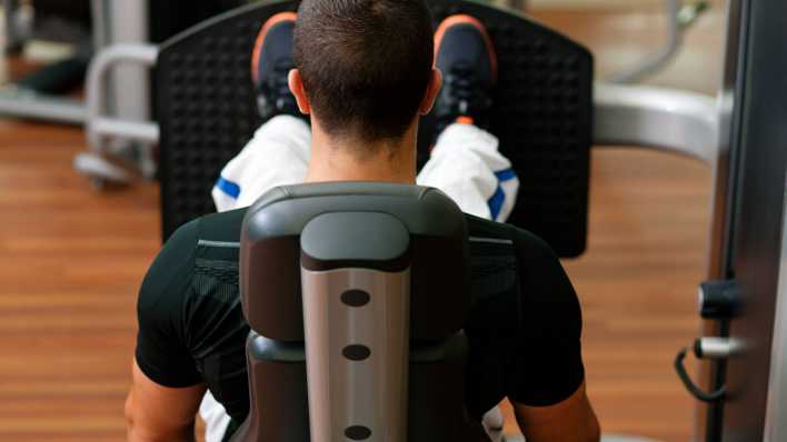 Mann trainiert im Fitnessstudio an der Beinpresse