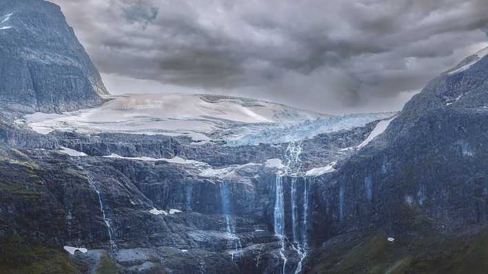 Das Wasser von einem schmelzendem Gletscher in Norwegen läuft an den Felswänden herab