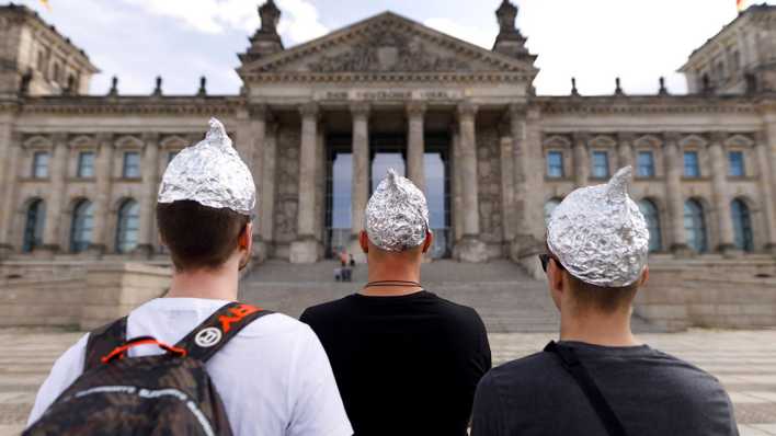 Männer mit Aluhüten protestieren vor dem Reichstagsgebäude. (Quelle: Picture Alliance)