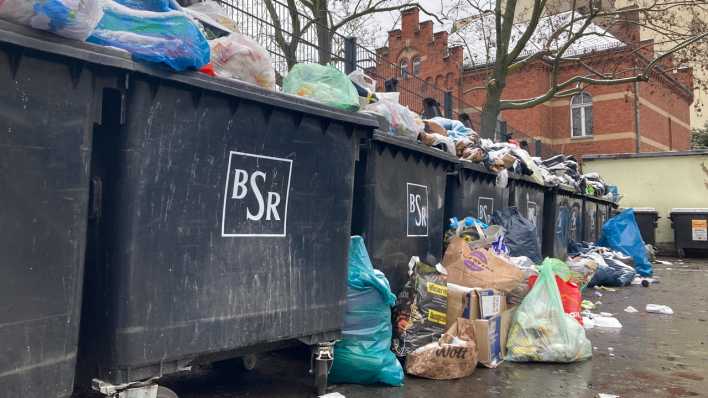 Müll liegt auf und neben aufgeklappten Mülltonnen in einem Berliner Hinterhof. (Bild: dpa)