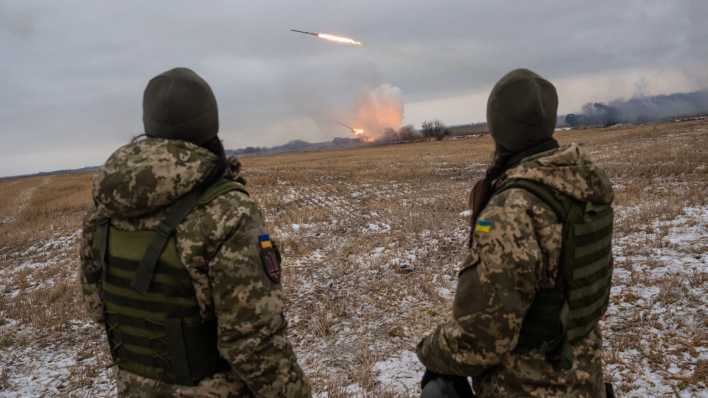 Zwei ukrainische Soldaten beobachten einen Flugkörper über einem Feld.