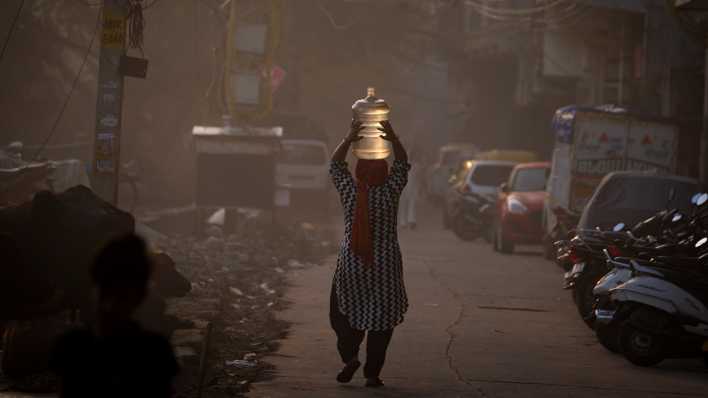 Eine Frau trägt einen Wasserkanister auf ihrem Kopf
