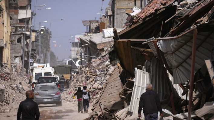 Menschen laufen durch zerstörte Straßenzüge in der türkische Stadt Antakya.