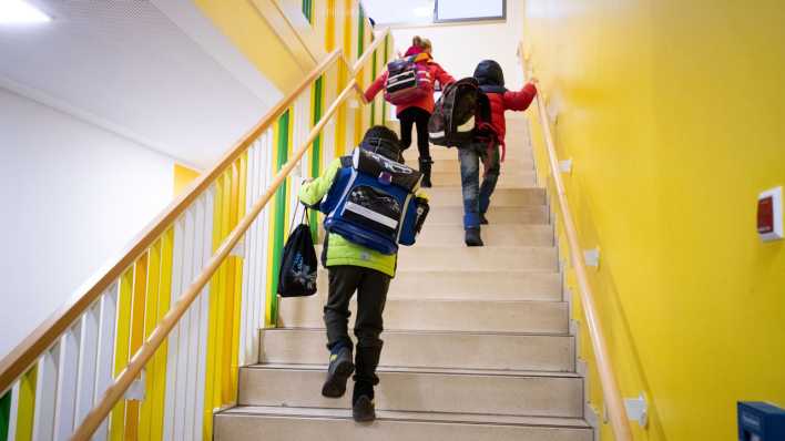 Grundschulkinder laufen mit ihren Schulranzen und Turnbeuteln über eine Treppe in ihr Klassenzimmer in einer Hamburger Schule (Bild: picture alliance/ dpa)