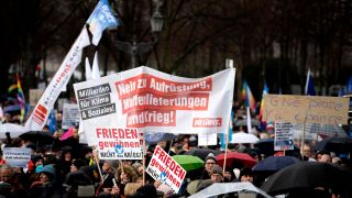 Ein Plakat der Partei die Linke fordert das Ende der Waffenlieferungen bei der Demonstration "Aufstand für den Frieden" am 25. Febraur 2023 in Berlin.