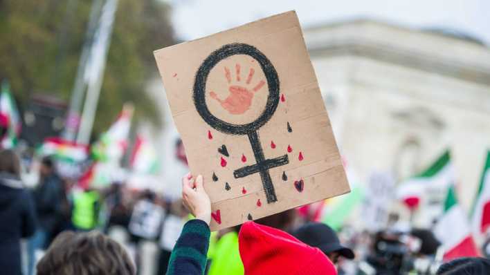 Ein Plakat bei einer Demonstration für Solidarität mit den Protesten im Iran zeigt ein Frauen-Zeichen.