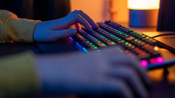 Ein Junge spielt an einer Gaming-Tastatur ein Videospiel.