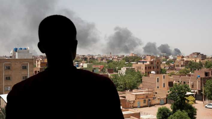 Eine Person guckt auf Rauch, der über der sudanesischen Hauptstadt Khartum aufsteigt (Bild: dpa)