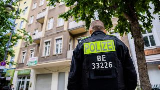 Ein Polizist steht bei einer Hausdurchsuchung gegen die Gruppe "Letzte Geneartion" in Berlin-Kreuzberg vor einem Gebäude. (Bild: dpa)