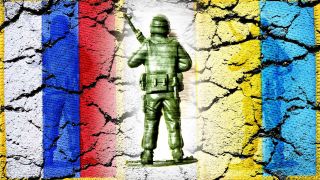 Soldatenfigur zwischen den Fahnen von Russland und der Ukraine (Bild: dpa)