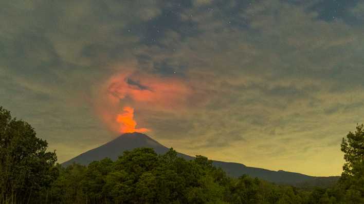 Der Vulkan Popocatepetl stößt in der Dämmerung Asche, Dampf und Gas aus.