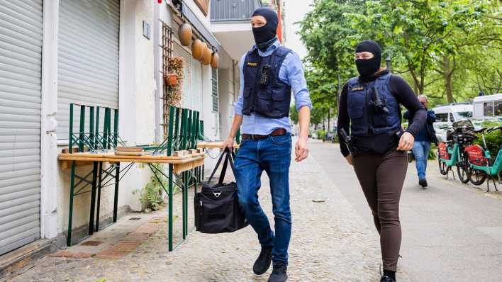 Polizisten gehen bei einer Hausdurchsuchung in Berlin-Kreuzberg zu einem Gebäude.