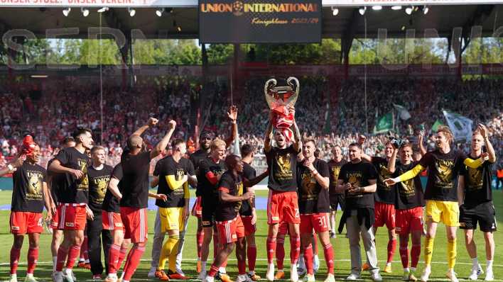 Die Spieler von Union jubeln nach ihrem Einzug in die Champions League mit einem Pokal aus Pappe in Richtung der Fans.