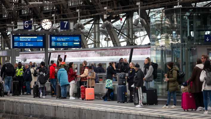 Bahnreisende warten auf dem Bahnsteig auf die Einfahrt eines Zuges im Kölner Hauptbahnhof.