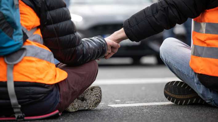 Klimaaktivisten der Gruppe "Letzte Generation" haben ihre Hände zusammengeklebt, um eine Hauptverkehrsstraße zu blockieren.