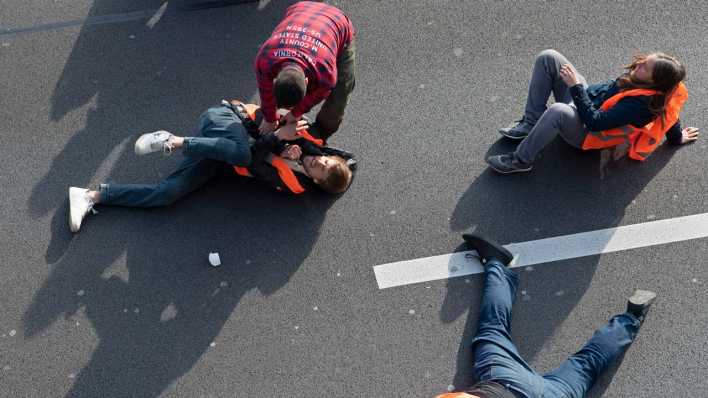 Ein Mann zerrt einen Aktivisten der Gruppe "Letzte Generation" bei einer Blockade auf der Stadtautobahn A100 unweit des Kurfürstendamm von der Straße.