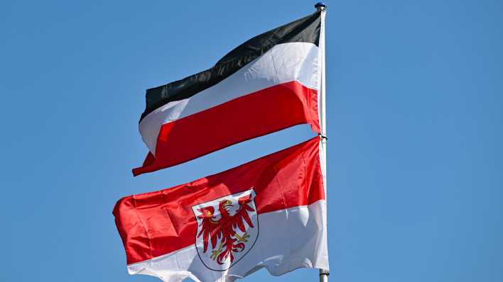 Die Reichsflagge des Kaiserreichs (schwarz-weiß-rote Reichsflagge) und die Fahne des Bundesland Brandenburg mir dem roten Adler, wehen im Wind an einem Mast auf einem privaten Grundstück in der Uckermark (Bild: dpa / Patrick Pleul)