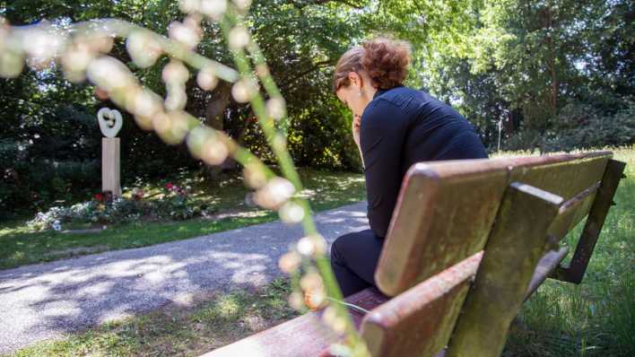 Eine Frau auf einer Bank trauert um ihr Kind