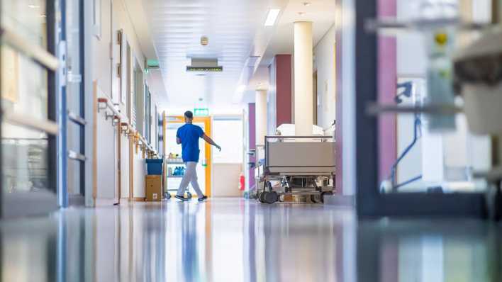 Ein Pfleger geht über den Gang einer Krankenhausstation am Universitätsklinikum Carl Gustav Carus in Dresden (Bild: IMAGO / Sylvio Dittrich)